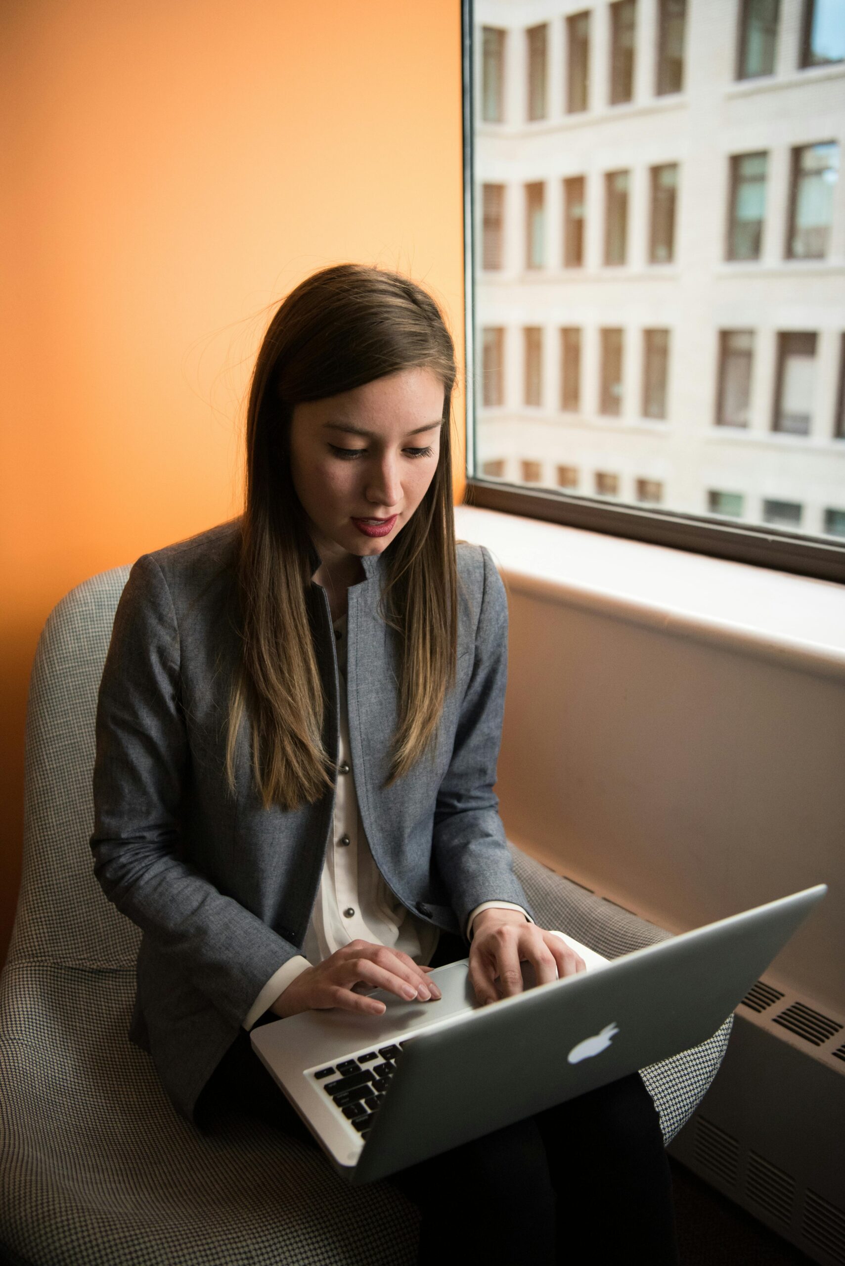 Businesswoman in office working remotely on a laptop by the window.